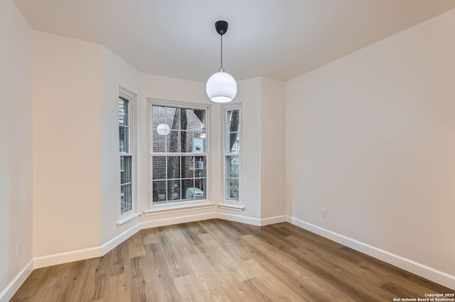 unfurnished dining area featuring baseboards and light wood-style flooring