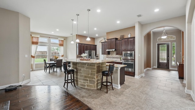 3318 Jasons, Marion, TX 78124 - kitchen with appliances with stainless steel finishes, arched walkways, dark brown cabinets, a breakfast bar, and a center island