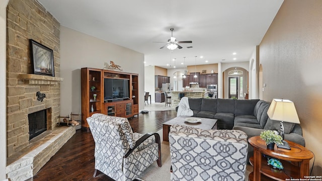3318 Jasons, Marion, TX 78124 - living area featuring a fireplace, ceiling fan, dark wood-style floors, and arched walkways