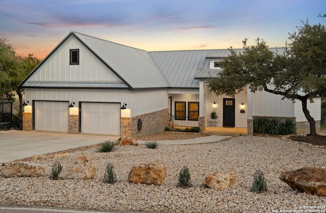modern farmhouse style home featuring brick siding, a porch, driveway, board and batten siding, and metal roof