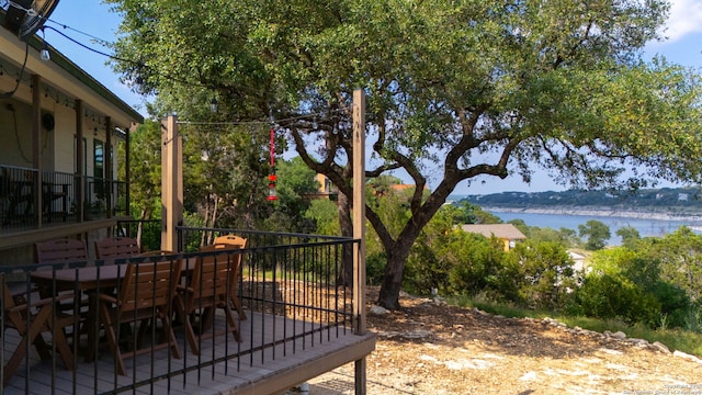 view of yard with outdoor dining area and a deck with water view