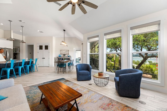 living area with ceiling fan, light wood-style floors, and lofted ceiling
