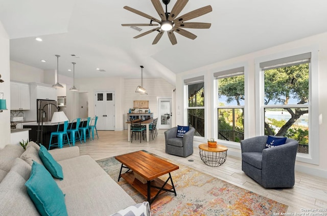 living room featuring a ceiling fan, light wood-style floors, recessed lighting, and lofted ceiling