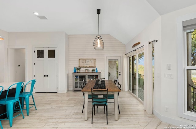 dining room featuring vaulted ceiling, light wood-style flooring, and baseboards