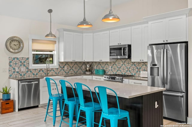 kitchen with appliances with stainless steel finishes, decorative backsplash, a center island, a breakfast bar area, and white cabinets
