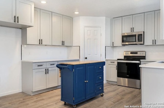 250 Oelkers, San Antonio, TX 78204 - kitchen featuring appliances with stainless steel finishes, blue cabinetry, light countertops, light wood-type flooring, and recessed lighting
