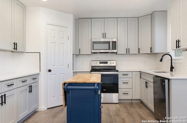 250 Oelkers, San Antonio, TX 78204 - kitchen featuring appliances with stainless steel finishes, a sink, light wood finished floors, and backsplash