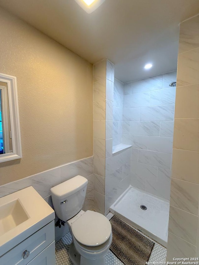 3084 Rustler, Canyon Lake, TX 78133 - bathroom featuring tile walls, a tile shower, tile patterned floors, toilet, and vanity