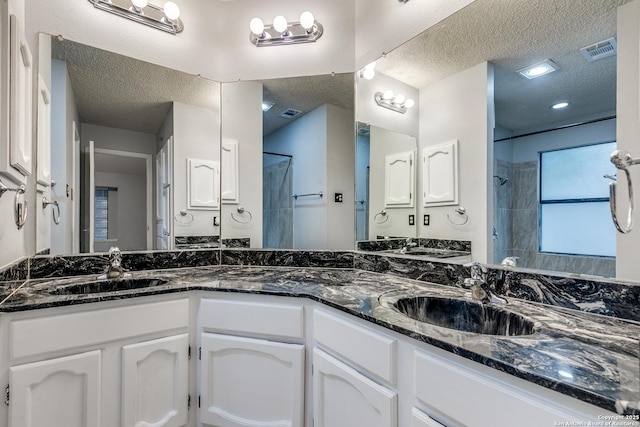 5615 Timber Bark, San Antonio, TX 78250 - bathroom featuring a textured ceiling, tiled shower, and double vanity