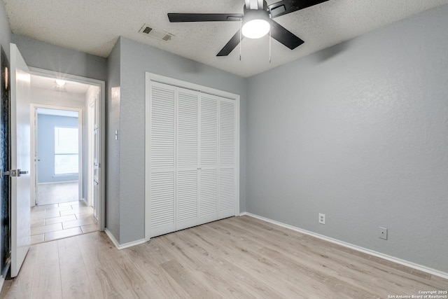 5615 Timber Bark, San Antonio, TX 78250 - unfurnished bedroom with light wood-style floors, a closet, baseboards, a textured ceiling, and ceiling fan