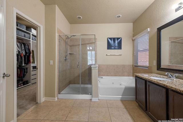 full bath featuring tile patterned floors, a stall shower, vanity, a tub with jets, and a textured ceiling
