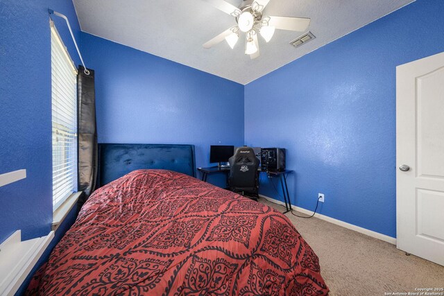 bedroom featuring carpet flooring, multiple windows, baseboards, a textured wall, and a ceiling fan