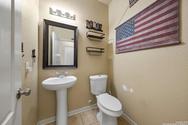 bathroom featuring tile patterned floors, toilet, a sink, and baseboards