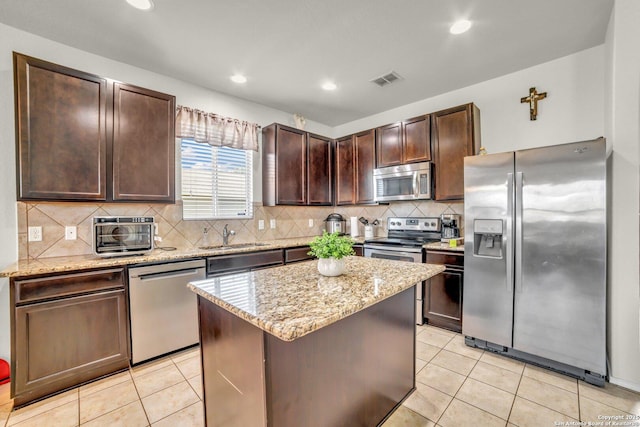 3628 Lazy Diamond, Selma, TX 78154 - kitchen with stainless steel appliances, dark brown cabinets, a center island, light stone counters, and recessed lighting