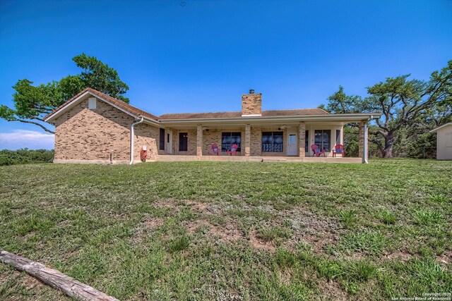 2721 Barton Hl, Bulverde, TX 78163 - rear view of house featuring a chimney, a lawn, and brick siding