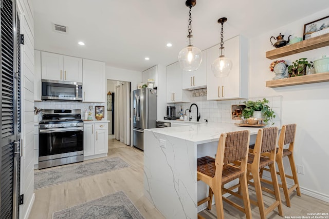 7500 Callaghan Rd Unit 108, San Antonio, TX 78229 - kitchen with stainless steel appliances, tasteful backsplash, a peninsula, light stone countertops, and a kitchen bar
