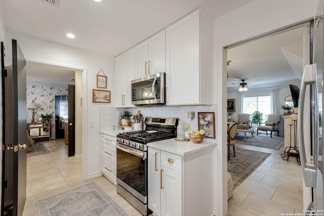 7500 Callaghan Rd Unit 108, San Antonio, TX 78229 - kitchen with stainless steel appliances, light countertops, white cabinetry, ceiling fan, and decorative backsplash