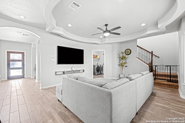 8502 Kallison Arbor, San Antonio, TX 78254 - living room with washing machine and dryer, arched walkways, a raised ceiling, a ceiling fan, and baseboards