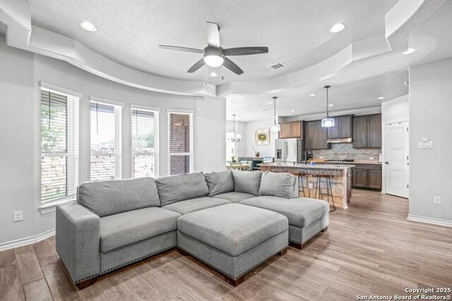 8502 Kallison Arbor, San Antonio, TX 78254 - living area featuring baseboards, a ceiling fan, light wood-type flooring, a tray ceiling, and recessed lighting