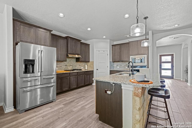 8502 Kallison Arbor, San Antonio, TX 78254 - kitchen with appliances with stainless steel finishes, a sink, arched walkways, light wood-style flooring, and a textured ceiling