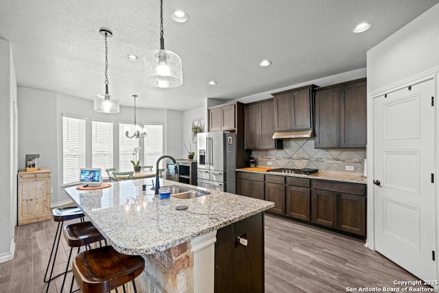 8502 Kallison Arbor, San Antonio, TX 78254 - kitchen with a sink, appliances with stainless steel finishes, a kitchen island with sink, backsplash, and light wood-type flooring