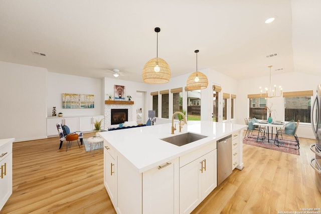2230 Bennett Ave, New Braunfels, TX 78132 - kitchen featuring a sink, stainless steel dishwasher, a fireplace, a chandelier, and light wood-type flooring