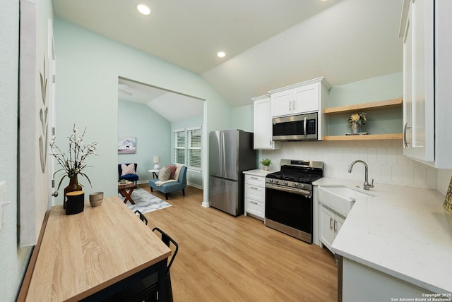 2230 Bennett Ave, New Braunfels, TX 78132 - kitchen with appliances with stainless steel finishes, a sink, lofted ceiling, backsplash, and light wood-style flooring