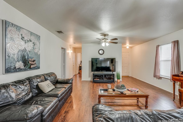 living area with a ceiling fan, wood finished floors, and a textured ceiling