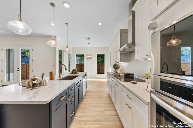 1310 S Mesquite, San Antonio, TX 78210 - kitchen featuring a sink, appliances with stainless steel finishes, light wood-style floors, wall chimney range hood, and plenty of natural light