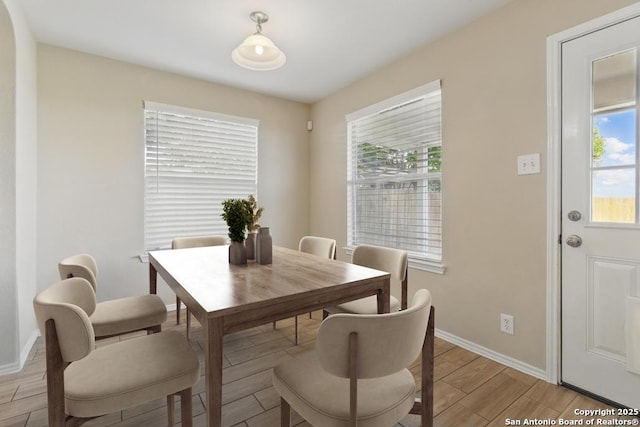 dining room featuring plenty of natural light, light wood-style floors, and baseboards