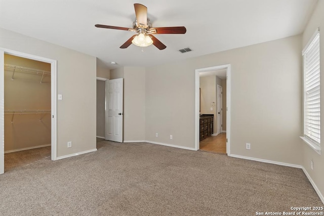unfurnished bedroom featuring a spacious closet, carpet flooring, baseboards, connected bathroom, and a closet