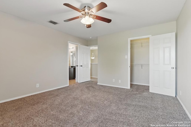 unfurnished bedroom featuring carpet floors, baseboards, a closet, and a walk in closet