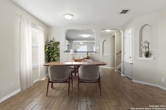 dining area with arched walkways, wood finished floors, and baseboards