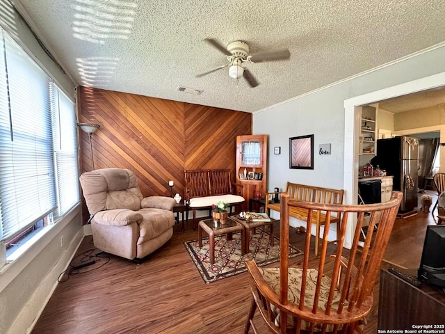 512 E Travis St, Luling, TX 78648 - living area with wood finished floors, ceiling fan, a textured ceiling, crown molding, and wood walls