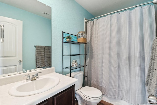 full bathroom featuring toilet, a textured wall, vanity, and shower / bath combo