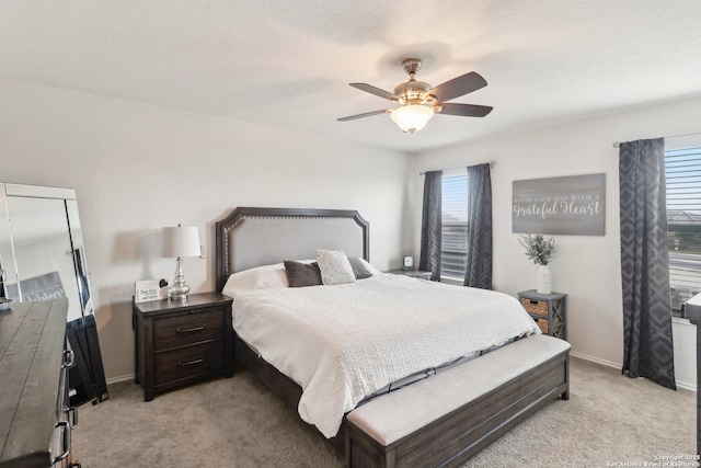 bedroom with light colored carpet, baseboards, and a ceiling fan