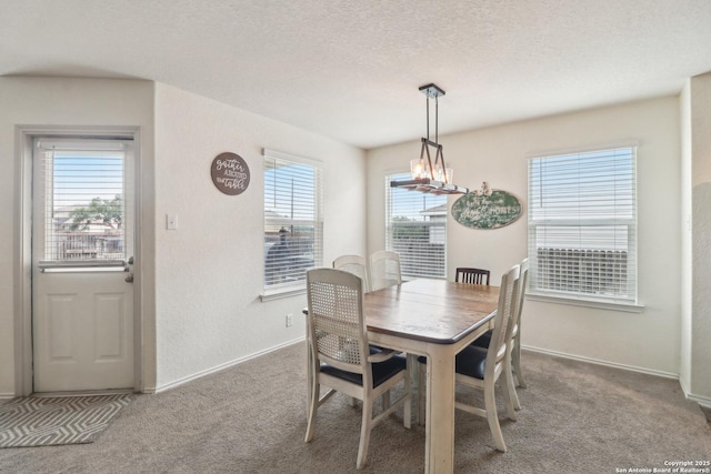 dining area featuring carpet floors, baseboards, and a textured ceiling