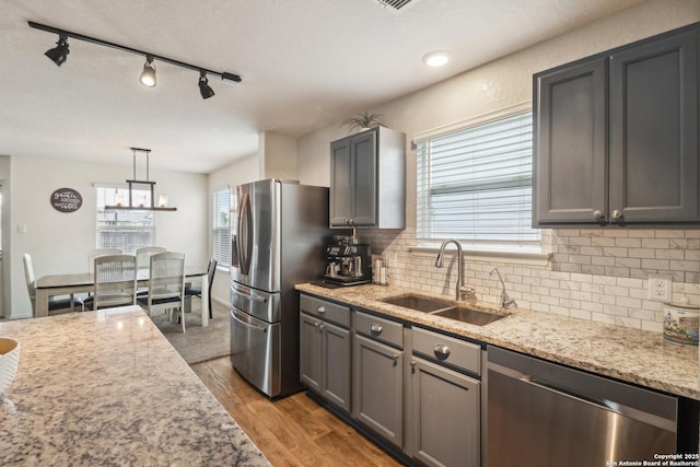 kitchen featuring stainless steel appliances, a sink, backsplash, and wood finished floors