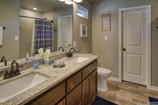 1139 Cedar Bnd, Canyon Lake, TX 78133 - bathroom with toilet, wood finished floors, tiled shower, double vanity, and a textured wall