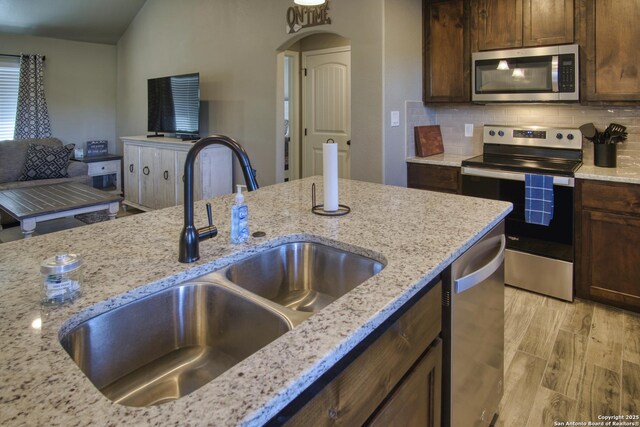 1139 Cedar Bnd, Canyon Lake, TX 78133 - kitchen with appliances with stainless steel finishes, a sink, light stone counters, and decorative backsplash