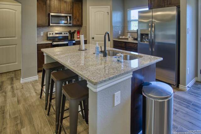 1139 Cedar Bnd, Canyon Lake, TX 78133 - kitchen featuring stainless steel appliances, a sink, tasteful backsplash, and light wood-style flooring