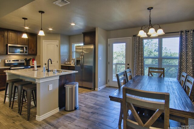 1139 Cedar Bnd, Canyon Lake, TX 78133 - kitchen featuring stainless steel appliances, a sink, baseboards, wood finished floors, and decorative backsplash