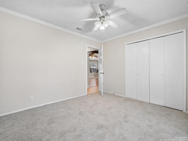 unfurnished bedroom featuring crown molding, a textured ceiling, carpet, baseboards, and a closet