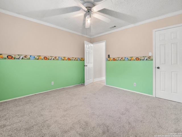 unfurnished room with carpet, ceiling fan, ornamental molding, a textured ceiling, and baseboards