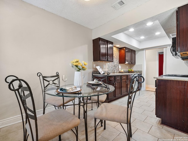 dining space with baseboards, a textured ceiling, a tray ceiling, recessed lighting, and light tile patterned floors