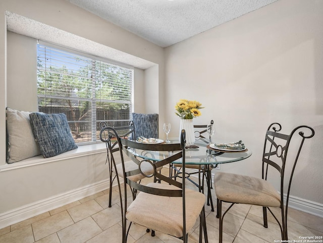 dining area with a textured ceiling, baseboards, and light tile patterned flooring