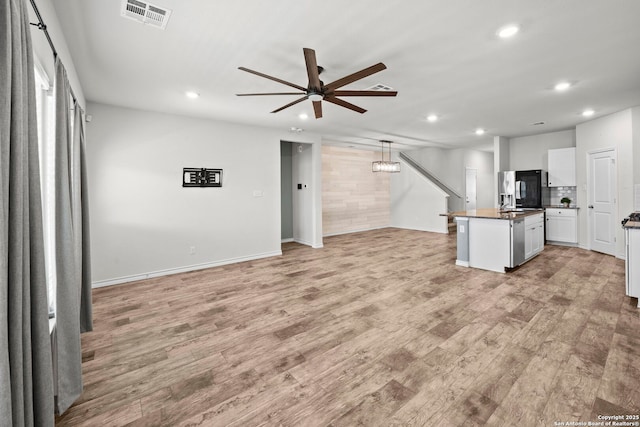 kitchen with recessed lighting, a ceiling fan, light wood finished floors, a center island, and white cabinets