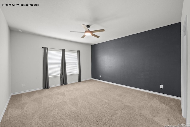 spare room featuring ceiling fan, light carpet, and baseboards