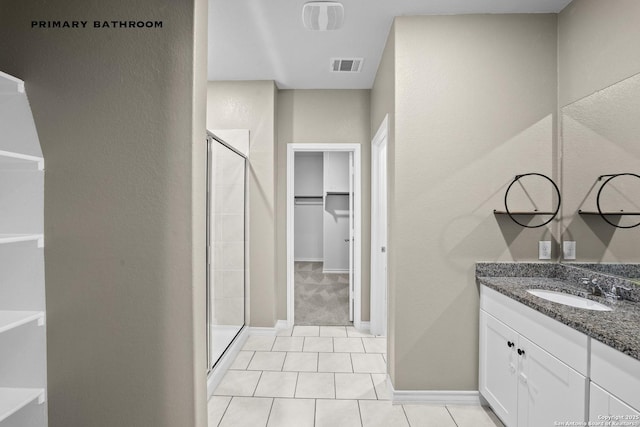 full bath with a shower stall, vanity, tile patterned flooring, a walk in closet, and a textured wall