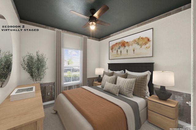 bedroom featuring carpet flooring, ceiling fan, and wainscoting